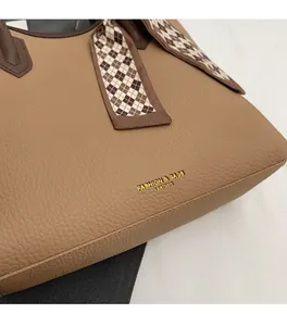 Detailed macro view of tan lychee grain leather tote with chic patterned silk scarf decor