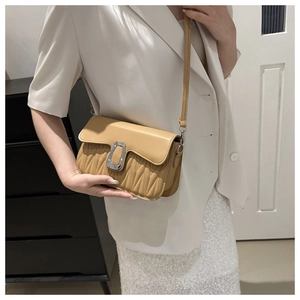 Detail view of beige crossbody bag with vertical pleats and rectangular metal buckle