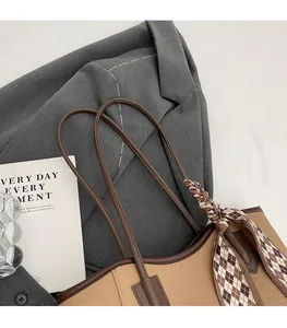 Detail of comfortable shoulder straps on a large camel brown tote bag with silk scarf charm
