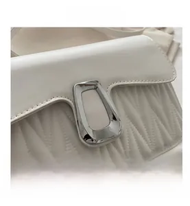 Close-up of white quilted leather bag featuring a silver geometric metal buckle