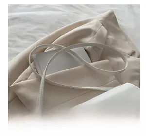 Close-up of adjustable strap and silver metal buckle on a white pleated shoulder bag