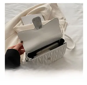 Detail of white quilted crossbody bag showing internal capacity for phone and cosmetics