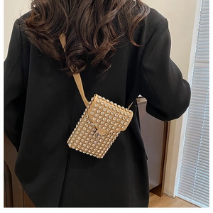 Dettaglio di una mini borsa a tracolla con strass scintillanti indossata su un blazer nero