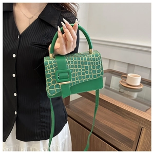 Detailed close-up of green crocodile embossed leather flap with gold square buckle accent