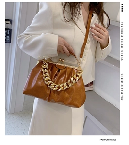 Detail showing brown pleated cloud bag with thick gold chain and metallic clasp