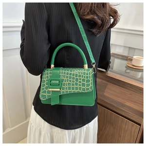 Green stone pattern handbag worn by a model in a stylish coffee shop setting