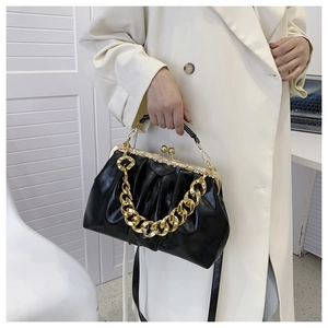 Detail of black pleated faux leather bag with vintage gold metal clasp and chain strap