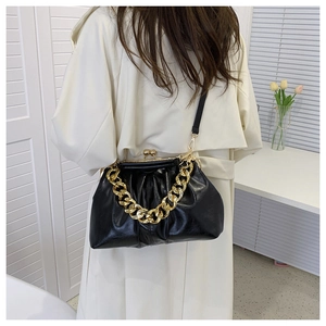 Detail of black pleated faux leather bag with vintage gold chain strap and metal clasp