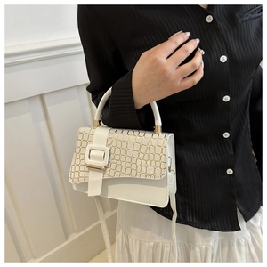 Detail of white handbag featuring crocodile embossed texture and gold buckle decoration