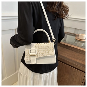 Detail of white stone texture handbag with golden crocodile flap and decorative buckle