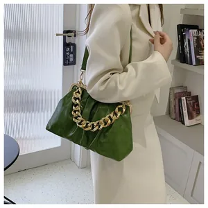 Close-up of green pleated dumpling bag with chunky gold chain on a blazer model