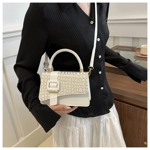 Detail of white crocodile texture handbag with gold trim and metallic magnetic buckle