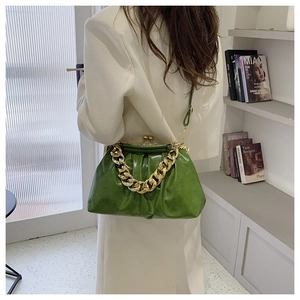 Detail of emerald green pleated cloud bag with gold chain strap on shoulder