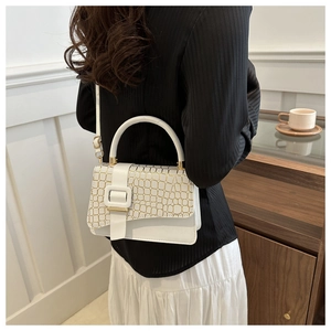 Detailed view of a white croc-embossed small square bag with golden hardware and handle