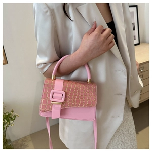 Detailed shot of pink crossbody bag with gold crocodile texture and metal buckle
