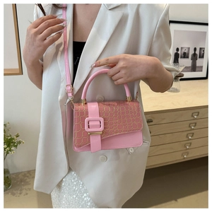 Pink crossbody bag with gold crocodile pattern flap and oversized buckle shown on a model