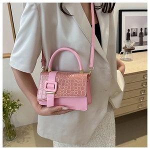 Detailed view of pink crossbody bag with crocodile pattern flap and square buckle