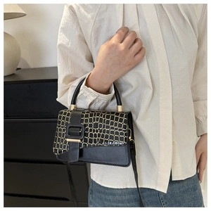 Detailed close-up of textured crocodile pattern leather and golden metallic clasp on bag