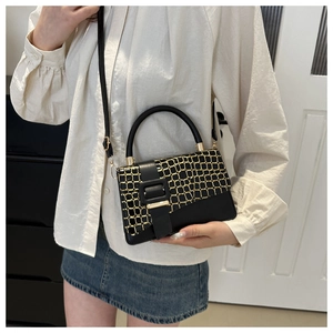 Fashionable black small square bag with golden crocodile pattern and handle on model
