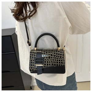 Detail of black faux crocodile leather texture and adjustable strap on a small crossbody bag