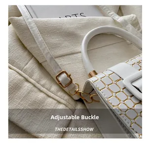 Detail of adjustable gold buckle on white faux leather handbag with crocodile texture