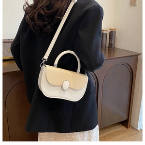 Detail of a cream color-block crossbody bag with woven texture and metal buckle on a model
