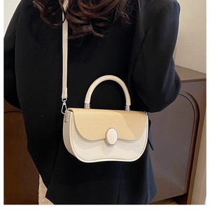 Detail of elegant two-tone faux leather and woven straw handbag with gold oval clasp
