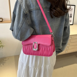 Rose pink quilted crossbody bag with silver U-shaped buckle on a model's shoulder