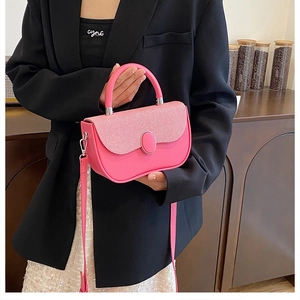 Detail of fuchsia leather handbag with striped texture and round buckle on black blazer