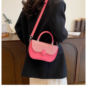 Detail of coral pink crossbody box bag featuring woven texture and oval clasp closure