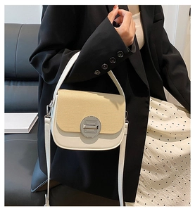 Detail of a beige woven box bag with white leather trim and round metallic magnetic clasp