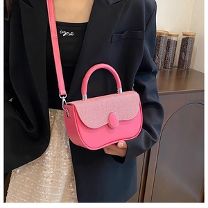 Detail of pink crossbody box bag with textured flap and elegant oval buckle on model