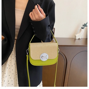 Detail view of the green straw-textured box bag featuring a round metal buckle and strap