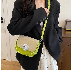 Close-up of contrast stitching crossbody bag with woven flap and green leather body