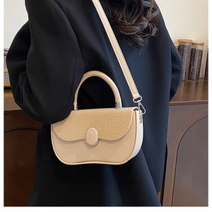 Detail of a beige woven contrast box bag with an oval buckle shown on a black blazer