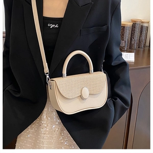 Detail of off-white crossbody bag with textured patchwork flap and oval buckle detail