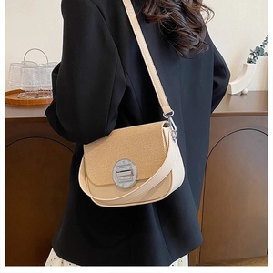 Detail of half-round beige patchwork bag with silver twist lock on a black blazer