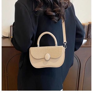 Close-up of beige crossbody bag with vertical texture and oval metal buckle on black suit