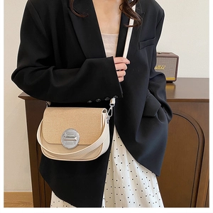 Detail of beige woven flap bag with silver buckle worn by model in a vintage setting