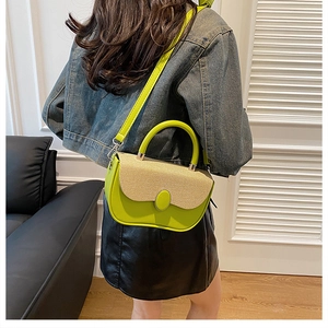 Detail of a bright green leather handbag with straw patchwork and a stylish arc base