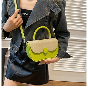 Detail of cross-body box bag with woven flap and decorative buckle held by a model