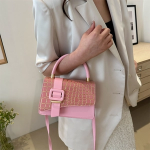 Pink stone pattern handbag with gold trim and crossbody strap in a modern room