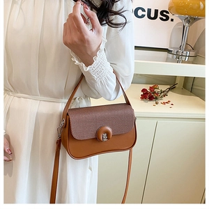 Dettaglio di borsa patchwork marrone con chiusura rotonda argento e tracolla rimovibile