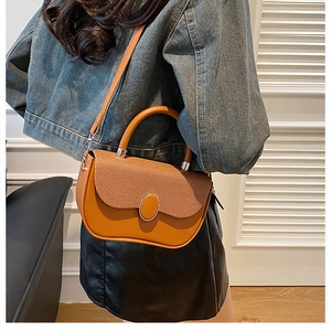 Detail of a brown leather and woven fabric crossbody bag worn by a model in a room
