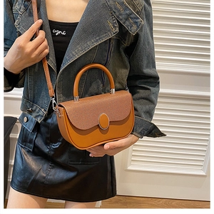 Detail of caramel crossbody bag with textured flap and oval metal buckle on a model
