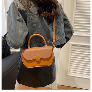 Detail of a brown textured crossbody bag with metal ring buckle on a fashion model