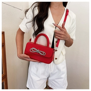 Detail of red leather square box bag featuring a sparkling silver bow-knot clasp