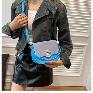 Detail of blue faux leather crossbody bag with striped fabric flap and silver turn-lock
