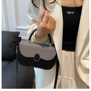 Detail of color-block crossbody bag featuring grey textured flap and metal oval buckle