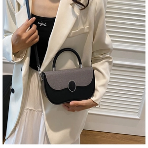 Detail of a textured two-tone crossbody box bag with metallic circular buckle